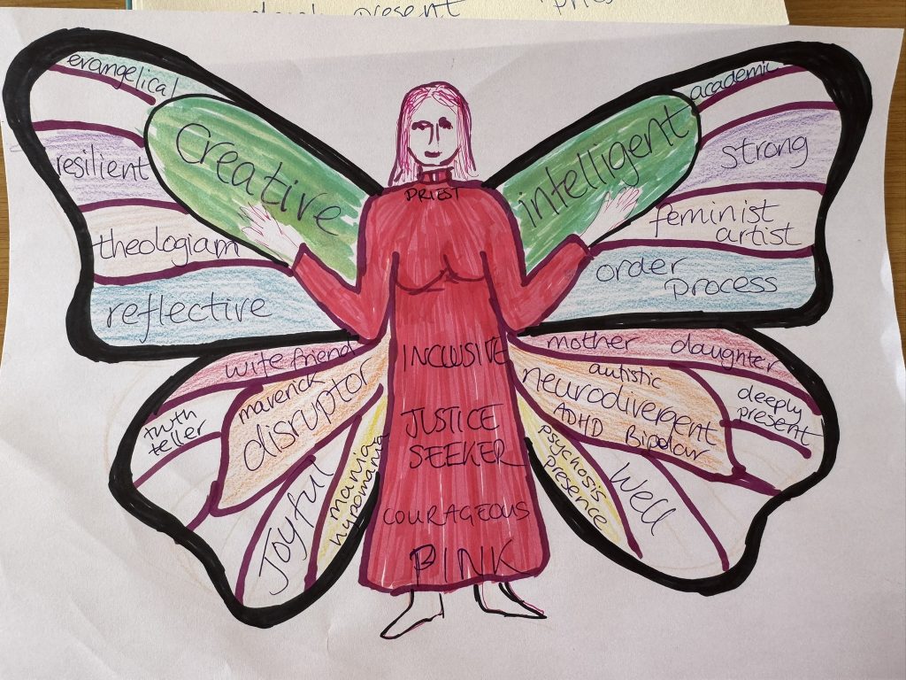 A drawing in felt tip and coloured pencils. A woman in wearing a pink dress with clerical colllar, standing with arms held open and upwards. Behind the woman are butterfly wings, with a black thick border around the edge of the wings. Each wing has different compartments, and colours, containing words like creative, intelligent, strong, resilient, reflective, wife, friend, mother, daughter, disruptor, neurodivergent, well, joyful etc